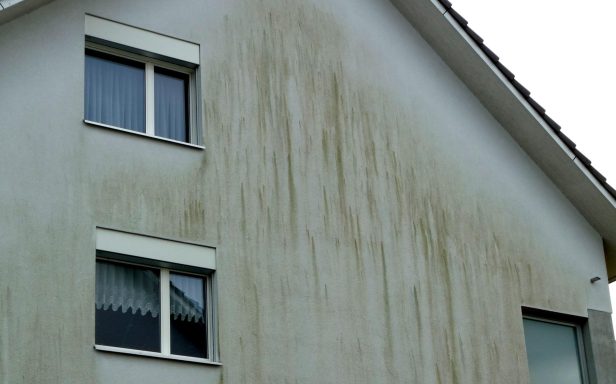 Fassade eines Hauses mit sichtbaren Wasserflecken und Verunreinigungen.